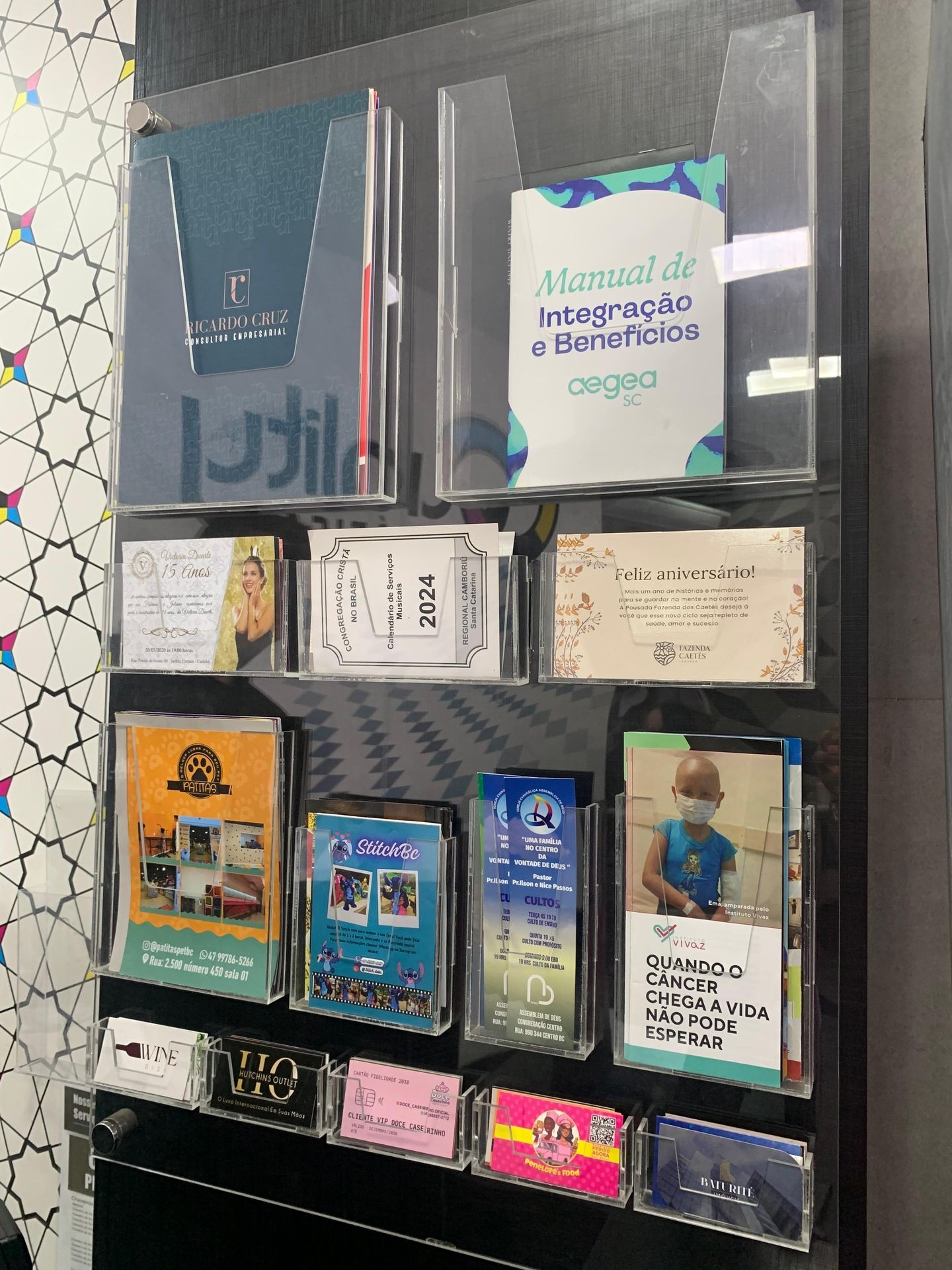 Wall display of various brochures and flyers in clear holders.